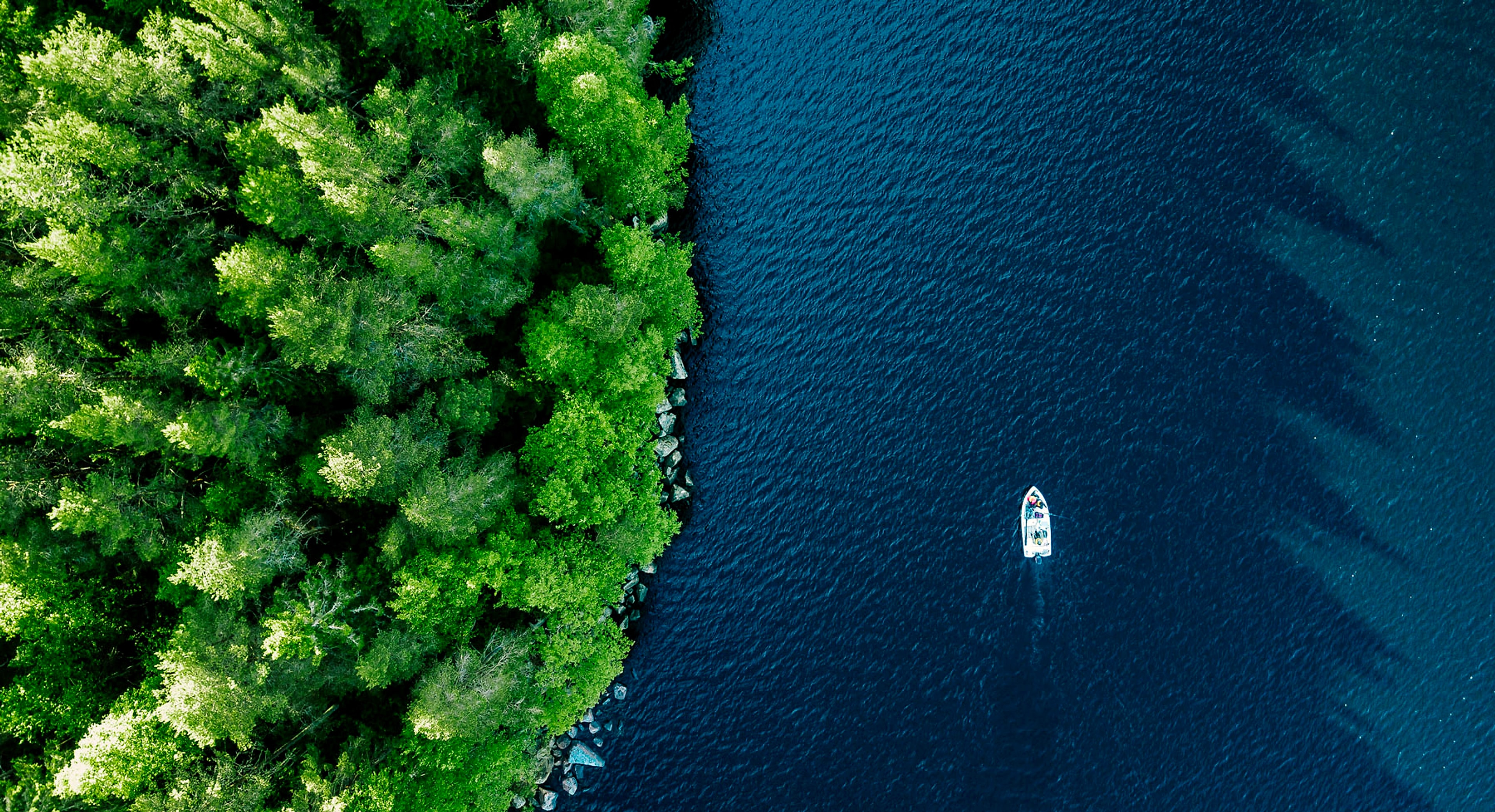 An aerial view of a boat crossing calm, deep water