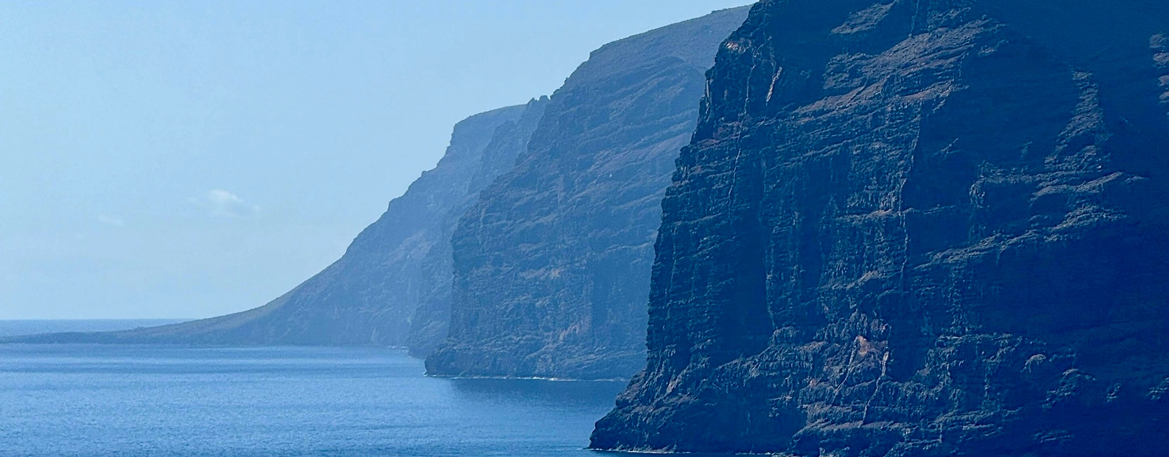 Sunlit sea cliffs rising above a calm ocean